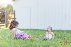sisters sitting in the grass at the barn