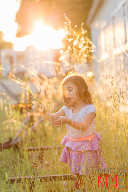 girl playing in the grass during sunset
