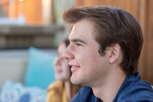 Side profile photo of boy with sister in background