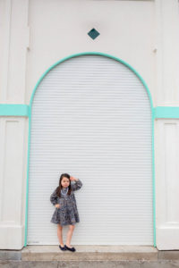 girl standing in front of white building with a pose