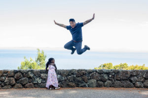 dad jumping in the air with daughter watching