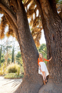 young girl standing at the base of a giant tree at stanford cactus garden
