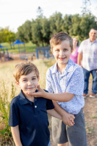 two brothers standing in front of their parents at the park