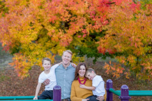 family of four in front of fall leaves