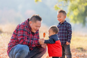 dad with two sons while he holds one leaf