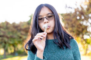 family photography san jose session with young girl wearing glasses and blowing dandelion