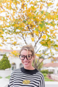 woman wearing glasses standing under a yellow tree