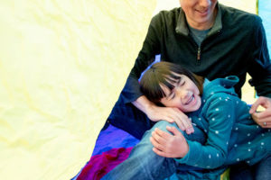 girl snuggling with her dad in a giant parachute