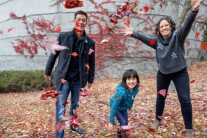 family of three throwing red leaves