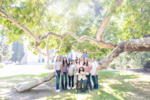 extended family session photo of everyone next to a giant tree with rainbow flare