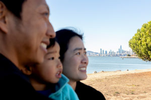family photos in oakland with family of three photo with san francisco skyline in focus
