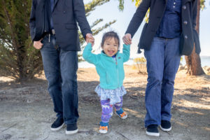 family photos in oakland with family of three of mom and dad holding their daughters hand