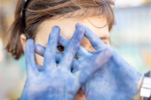 girl looking through her blue hands