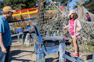 girl climbing a blue wooden horse at adventure playground in berkeley