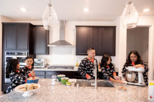 family of five baking cookies in the kitchen while wearing penguin pajamas for their family holiday traditions photography session