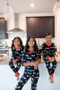 three siblings in the kitchen wearing penguin pajamas for their family holiday traditions session