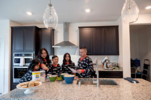 family of five wearing christmas pajamas in the kitchen for their family holiday traditions of baking cookies