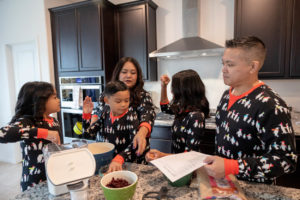 family of five wearing holiday pajamas and baking cookies for their family holiday traditions photography session