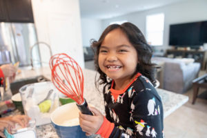 girl holding a baking whisk in the kitchen