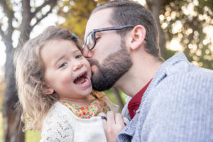 dad kissing daughter on her cheeks