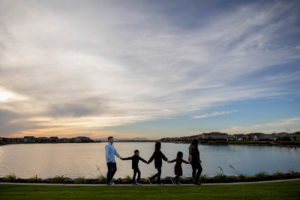 family of five walking by a lake during sunset