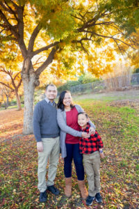 family of three next to fall leaves for their fall portraits
