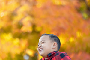 young boy laughing with fall colors in the background