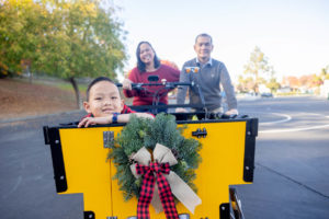 family of three on a bunch bike for their outdoor fall family photos in san jose