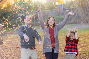 family of three tossing leaves up in the air