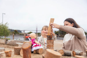 little girl playing with wooden blocks with her mom and baby doll at presidio tunnel tops