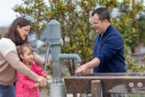 family of three playing with a water pump