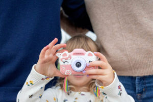 little girl holding a toy camera taking a photo of the photographer