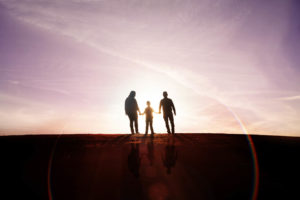 family of three silhouette photography with a rainbow flare and reflection