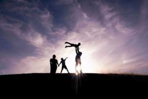 family of four silhouette photography with dad tossing their son up in the air