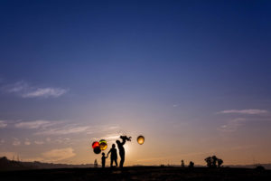 family of four holding balloons and playing with son