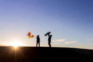 family of three silhouette photograph with mom holding balloons and dad tossing son up in the air