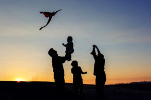 family of four flying a kite during a silhouette photograph