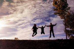 family of three jumping for their silhouette photograph