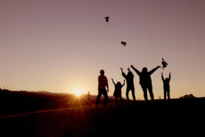family of five throwing stuffed animals up in the air for silhouette photography during sunset