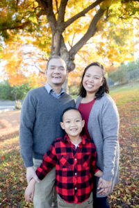 family of three wearing reds with yellow trees for their family photos
