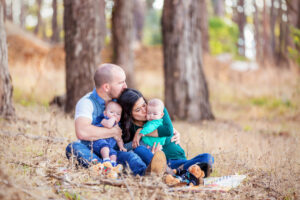 family of four wearing blues next to a forest for their family photos