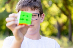 Tween boy holding up a rubik's cube to the camera
