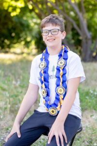 tween boy wearing a elementary promotion money lei for his photo session