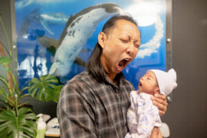 dad pretending to yawn with his newborn baby