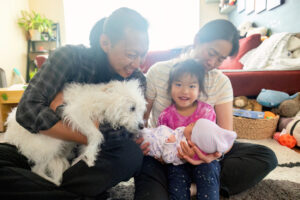 family of four with their newborn baby and dog in the lap of the dog