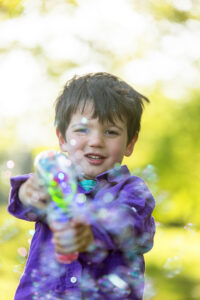 toddler boy playing with bubble machine