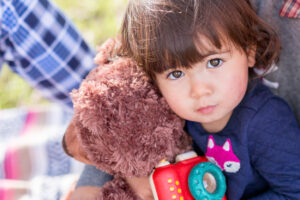 toddler girl holding a bear and camera