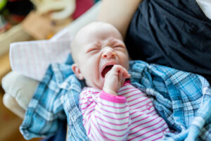baby yawning and wearing stripes with plaid blanket