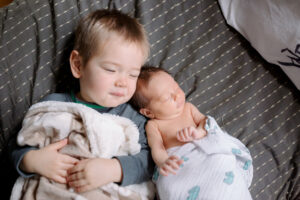 newborn baby snuggling with older sibling