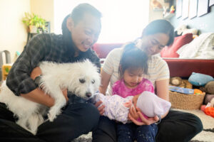 family of four holding a newborn baby and a dog